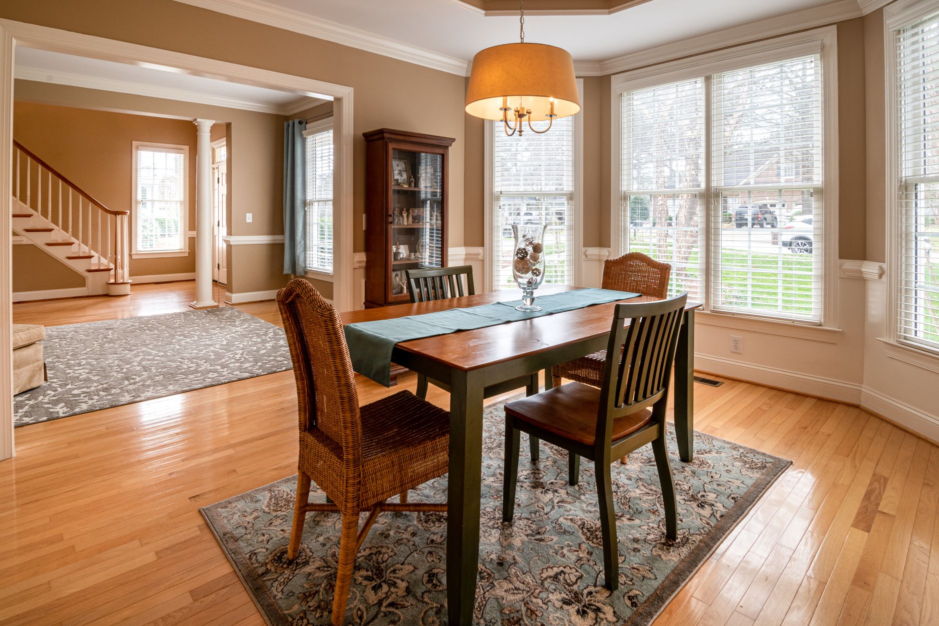 A sunlit dining room featuring a wooden table and wicker chairs, showcasing luxury interior design.