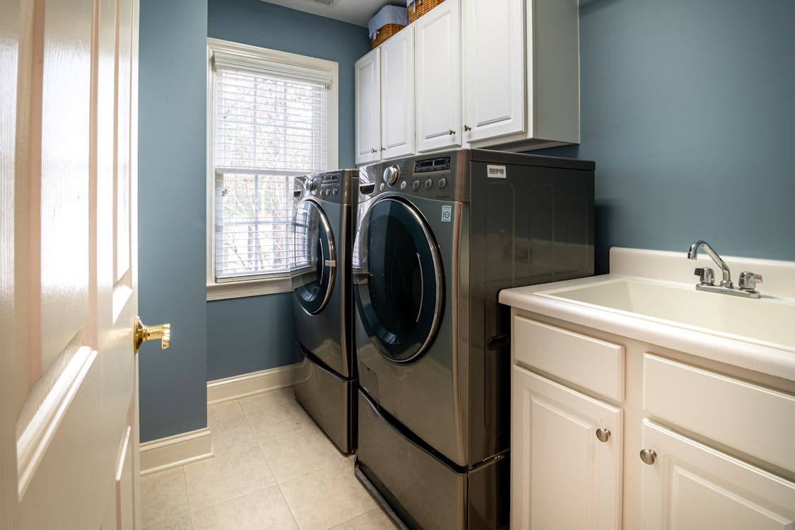 Free Front Load Washing Machine Beside White Window Blinds Stock Photo