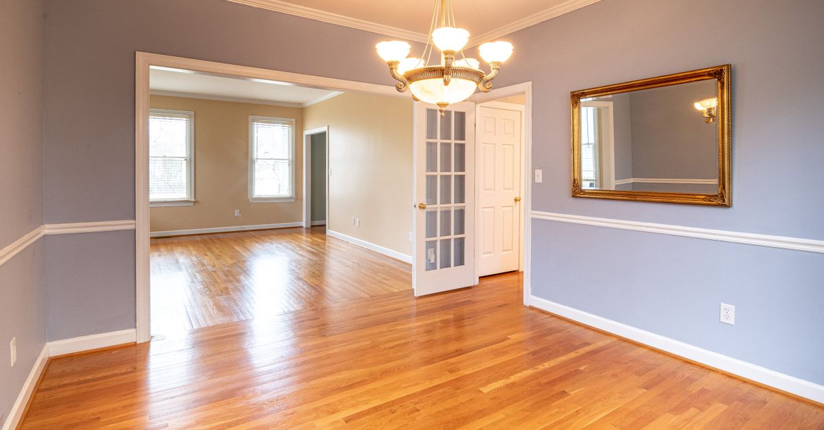 Bright residential room with hardwood floor and chandelier, ideal for real estate listings.