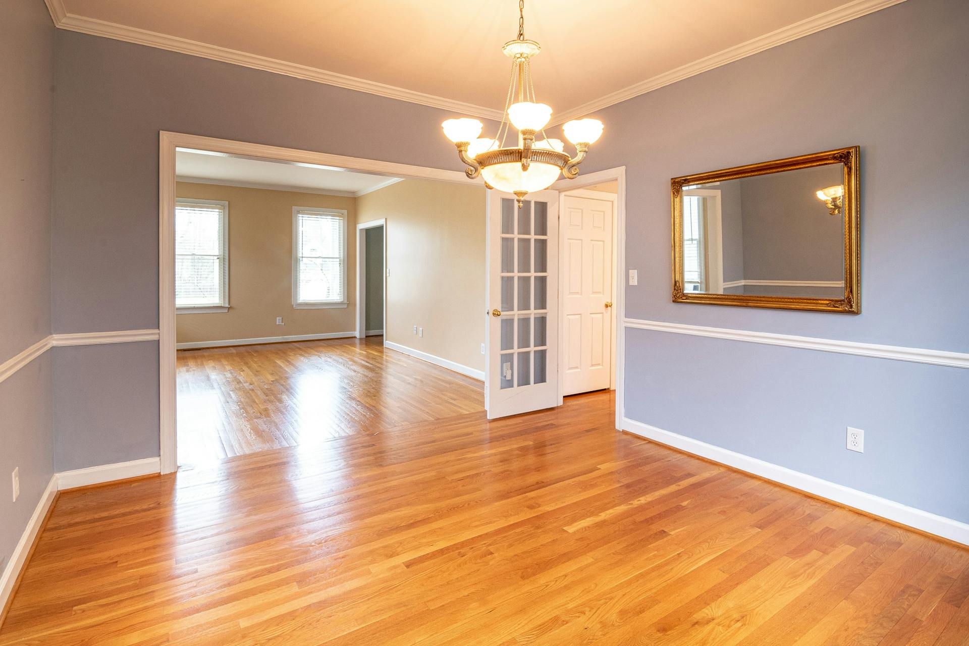 Bright residential room with hardwood floor and chandelier, ideal for real estate listings.