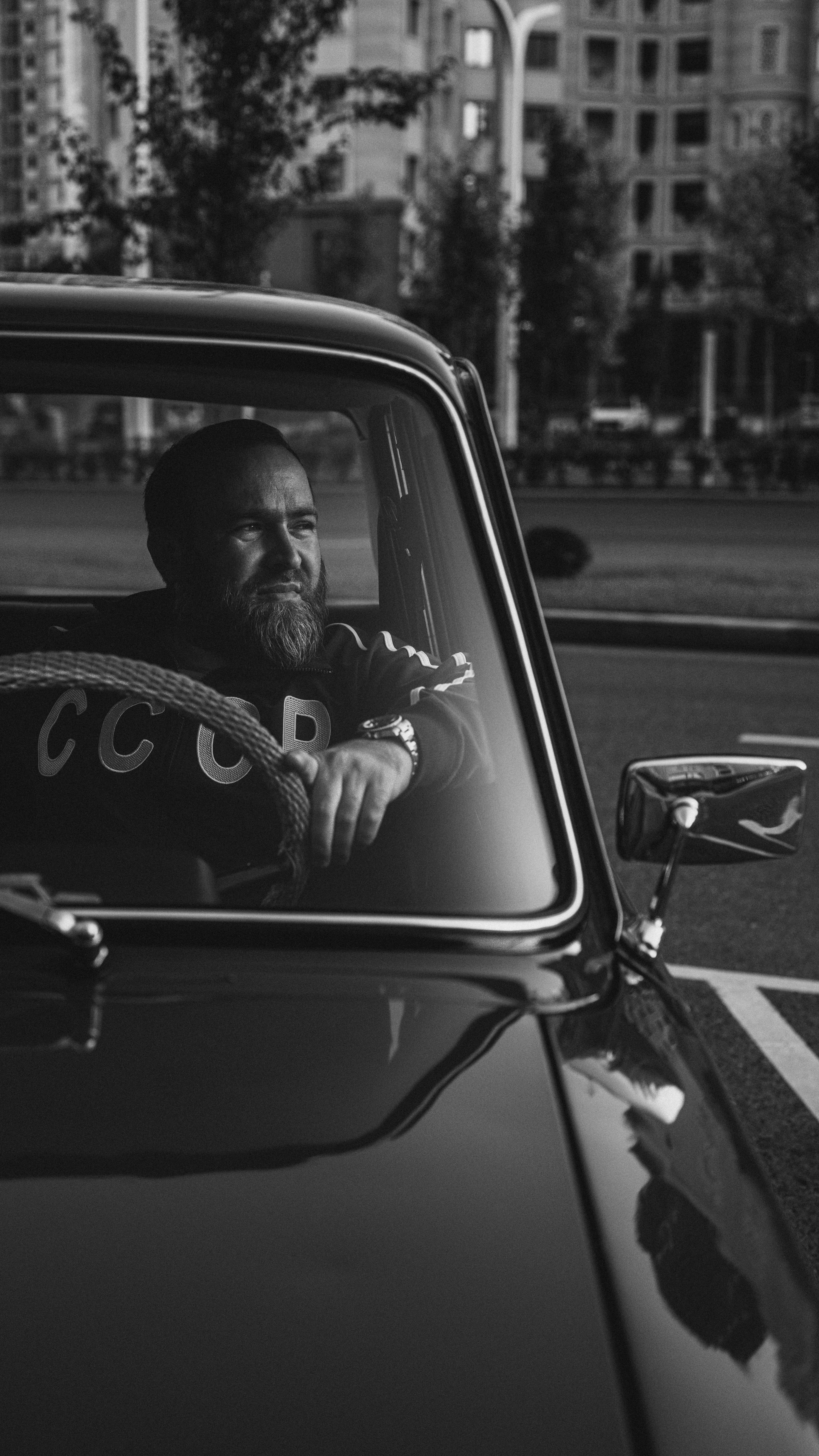 A man driving a classic car in Grozny, Chechnya in a nostalgic black and white style.