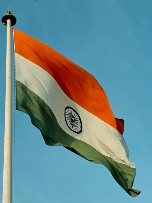 Free Vibrant Indian national flag waving against a clear blue sky, symbolizing patriotism and freedom. Stock Photo