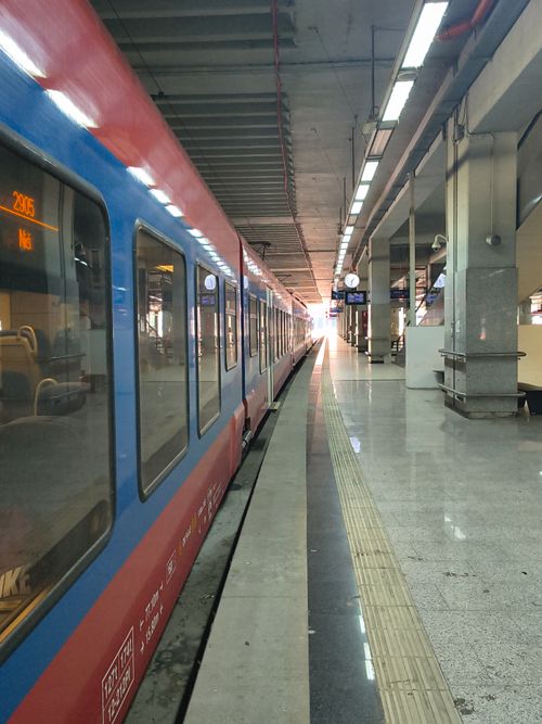 Free A modern train station with an empty platform, featuring a colorful train awaiting departure. Stock Photo