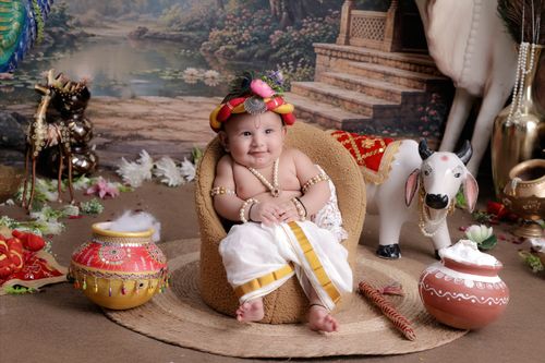 Free Adorable baby dressed in traditional Indian costume sitting amidst cultural artifacts. Stock Photo