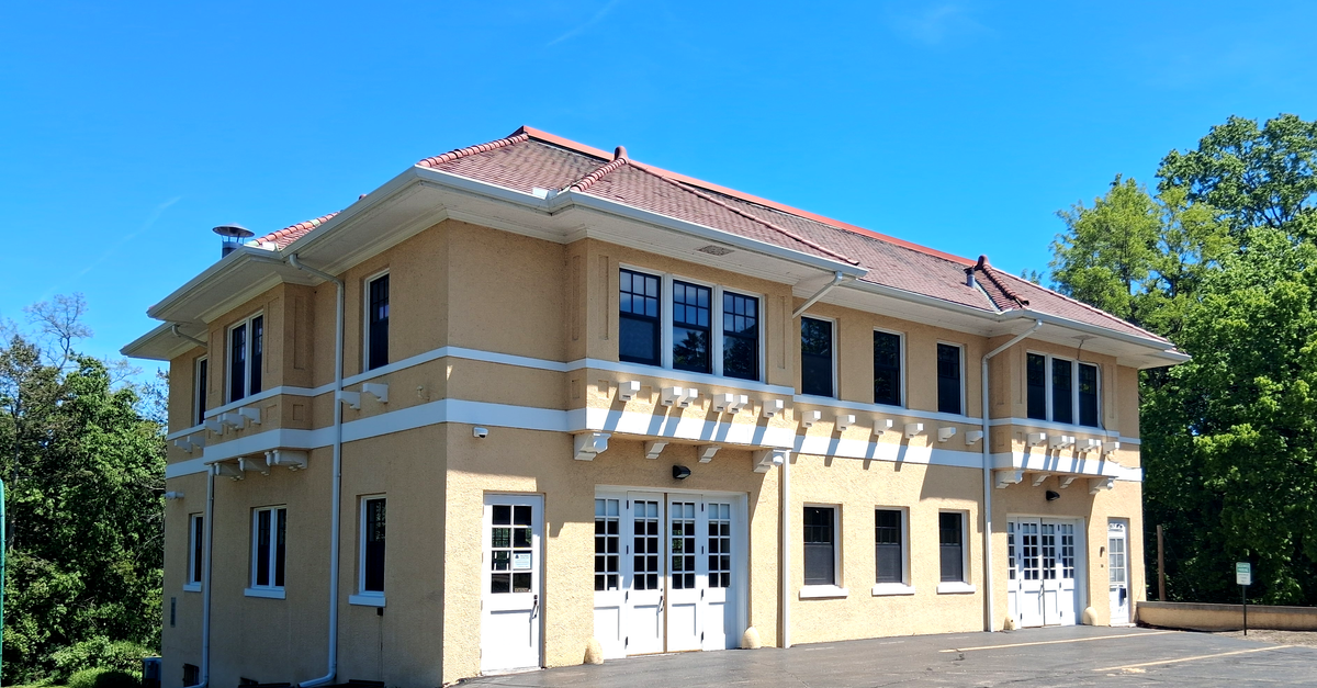 A beautiful two-story beige building with a red roof on a sunny day.