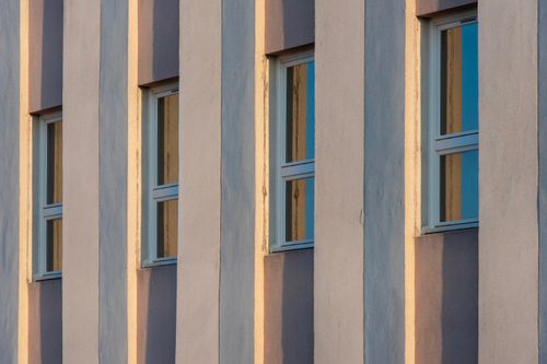 Free Exterior view of a modern building facade with sunlit windows and architectural shadows. Stock Photo