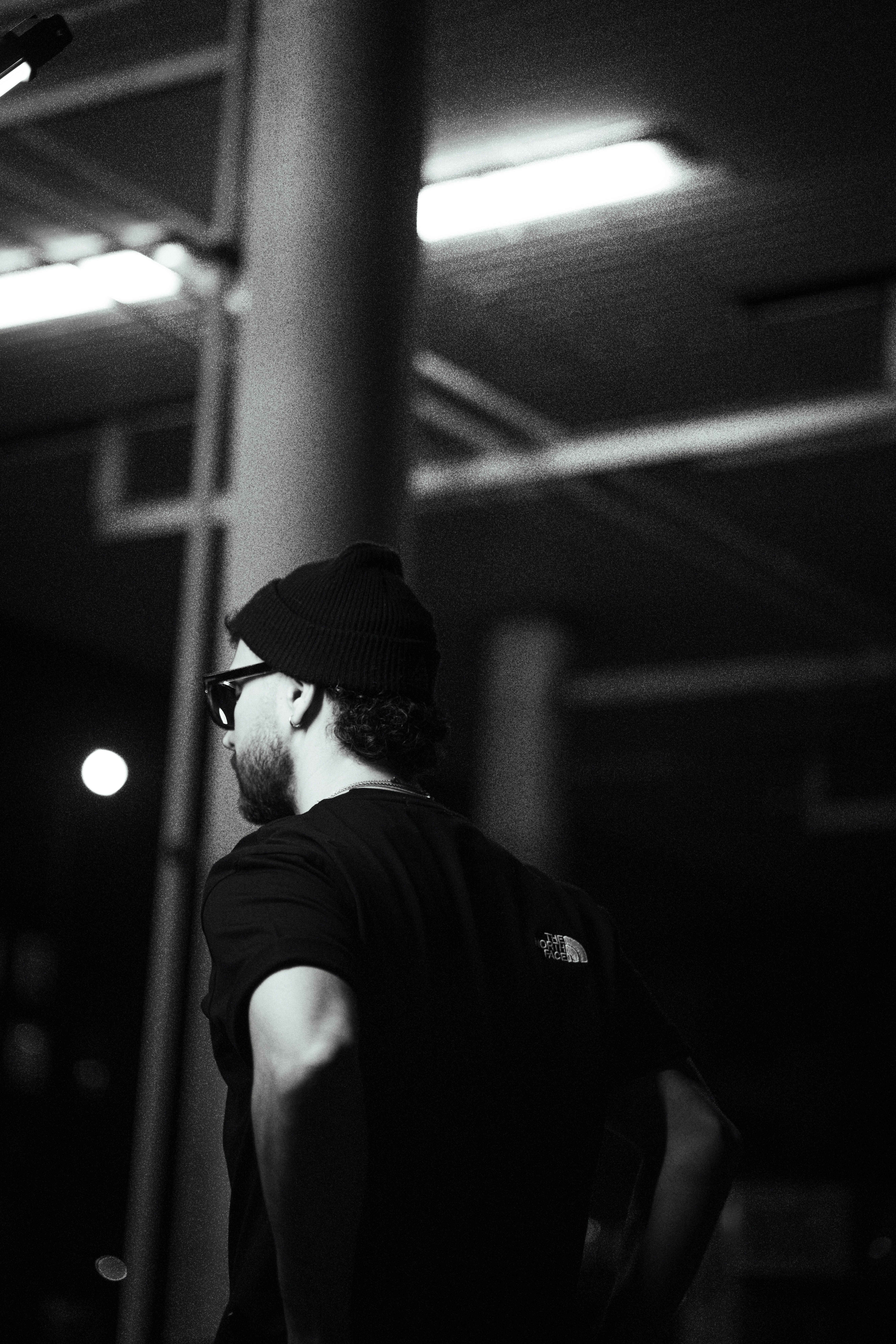 Black and white portrait of a fashionable man at nighttime, exuding urban style and moody vibes.