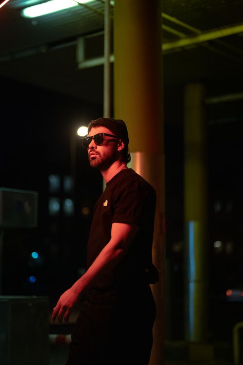 Free Moody night shot of a stylish man in sunglasses at a gas station, showcasing urban street fashion. Stock Photo