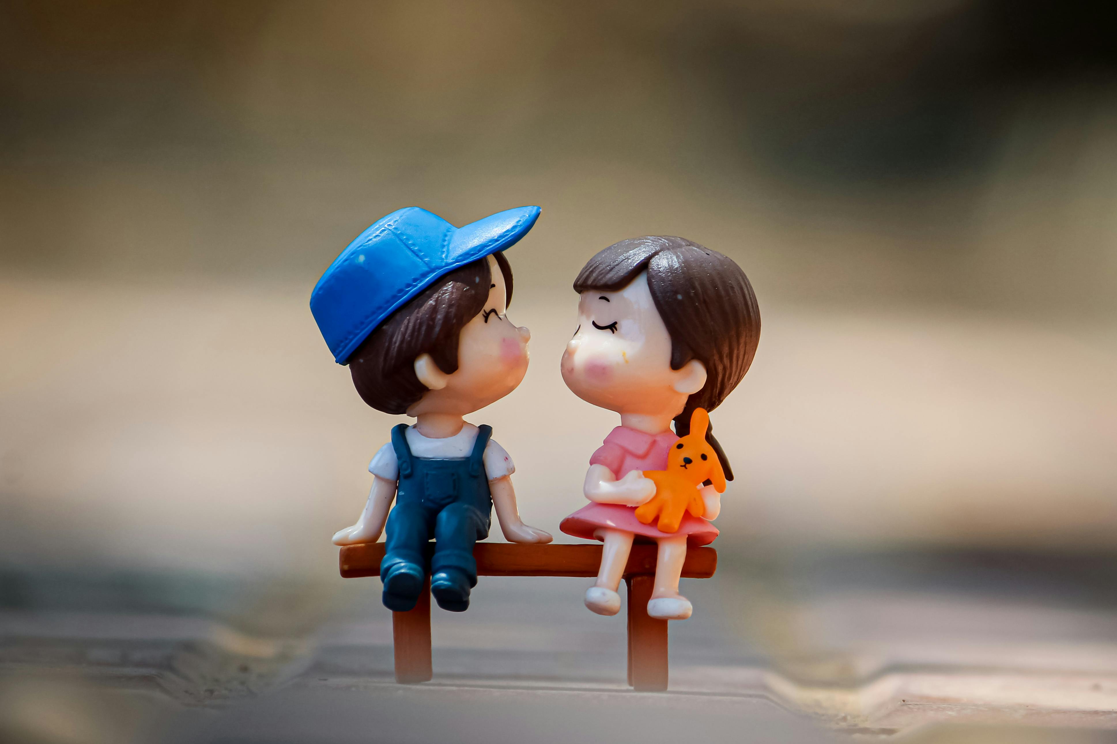 Figurine of boy and girl on bench · Free Stock Photo