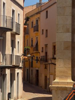 Explore a picturesque narrow street lined with historic buildings in Tarragona, Spain.