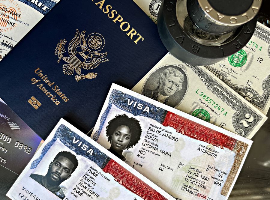 A United States passport with visa pages, stamps, and currency on a surface
