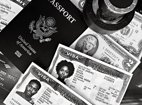 A black and white composition of a US passport, visas, and currency, showcasing travel essentials.