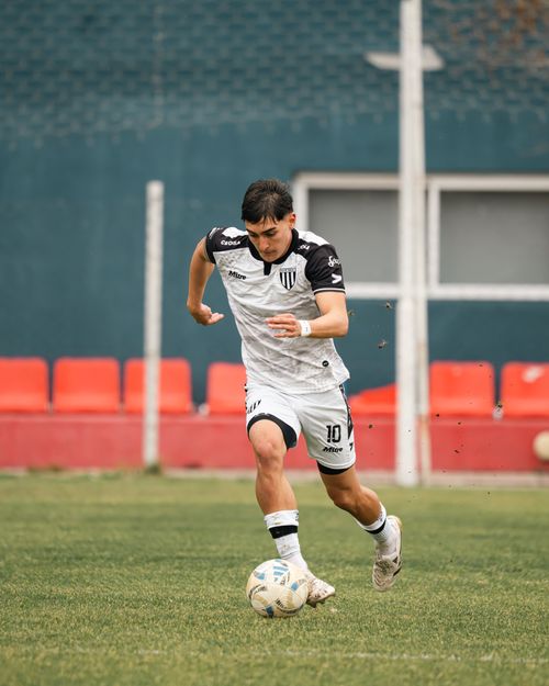 Free Athlete in white uniform dribbles the ball on a soccer field during daytime. Stock Photo