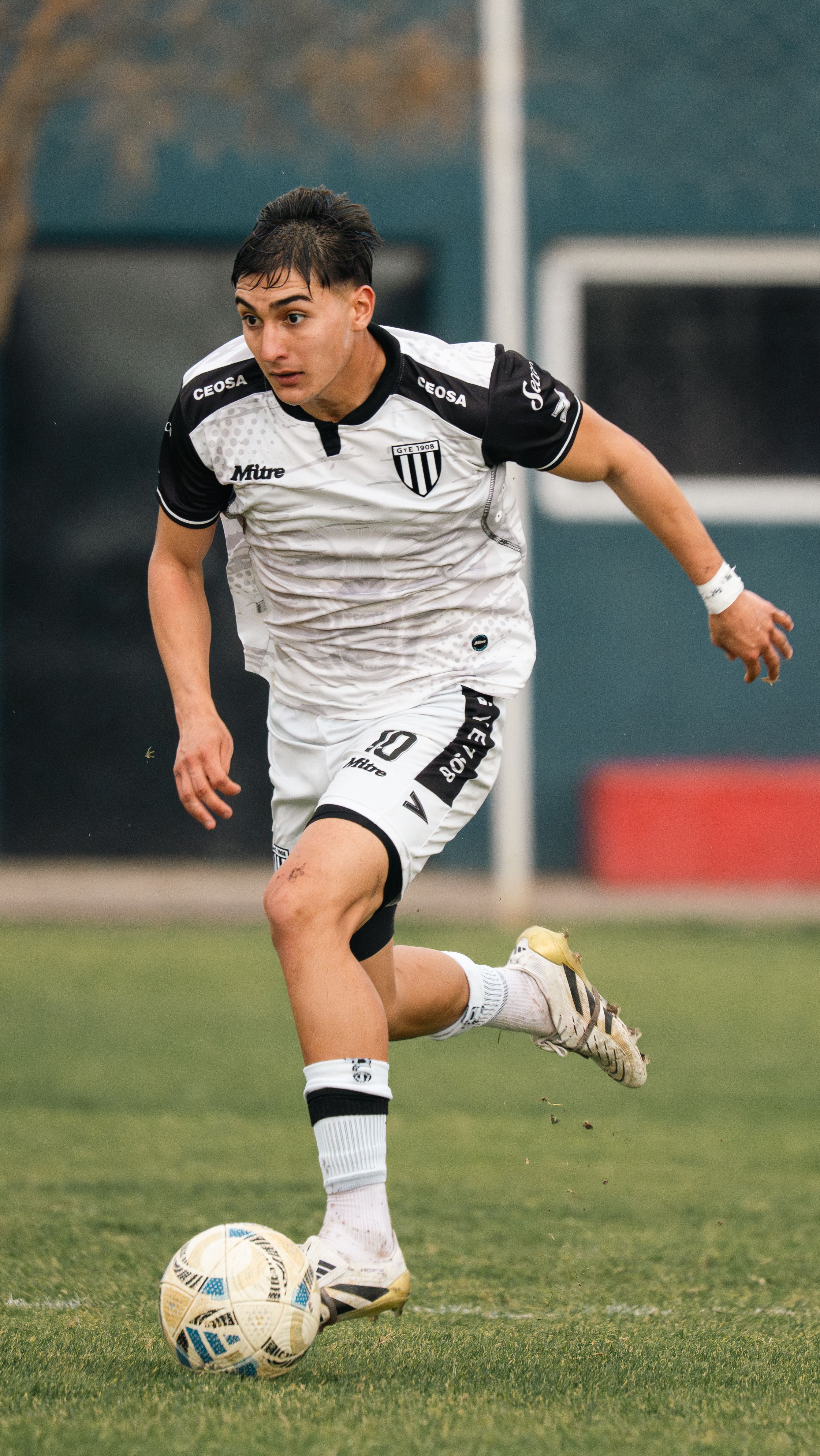 Dynamic shot of a male soccer player dribbling a ball during a match outdoors.
