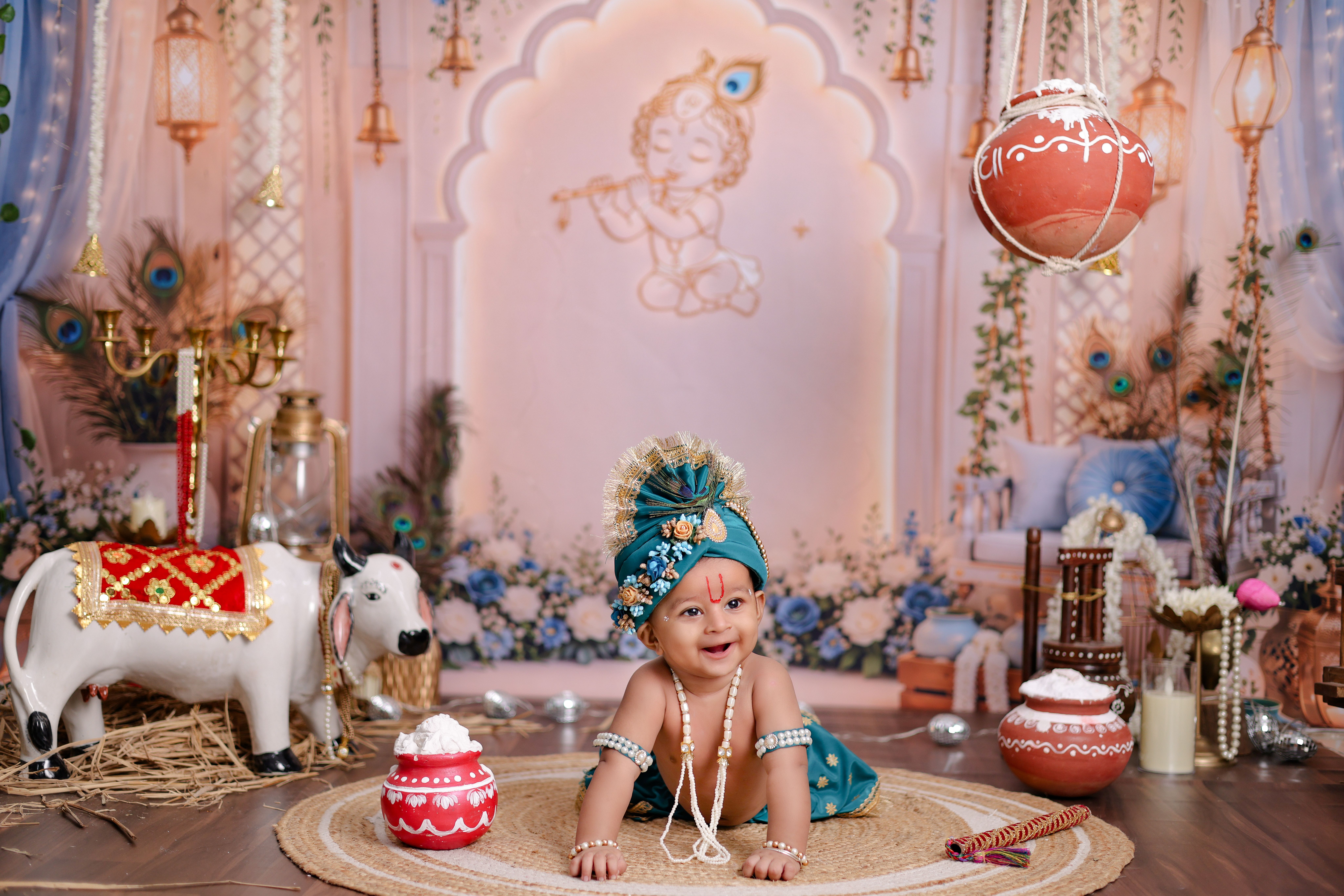 Charming baby in traditional Indian attire amidst Hindu Krishna festival decor.