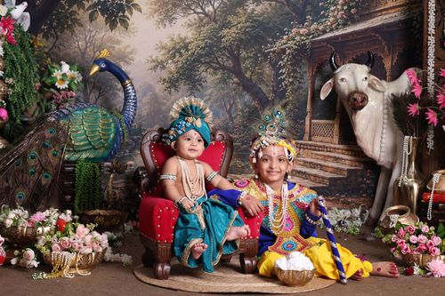 Free Children dressed as Krishna for Janmashtami celebration with cow and peacock decor. Stock Photo