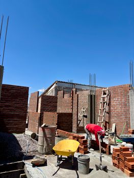 Construction worker building brick walls under clear blue sky in Ayacucho, Peru.
