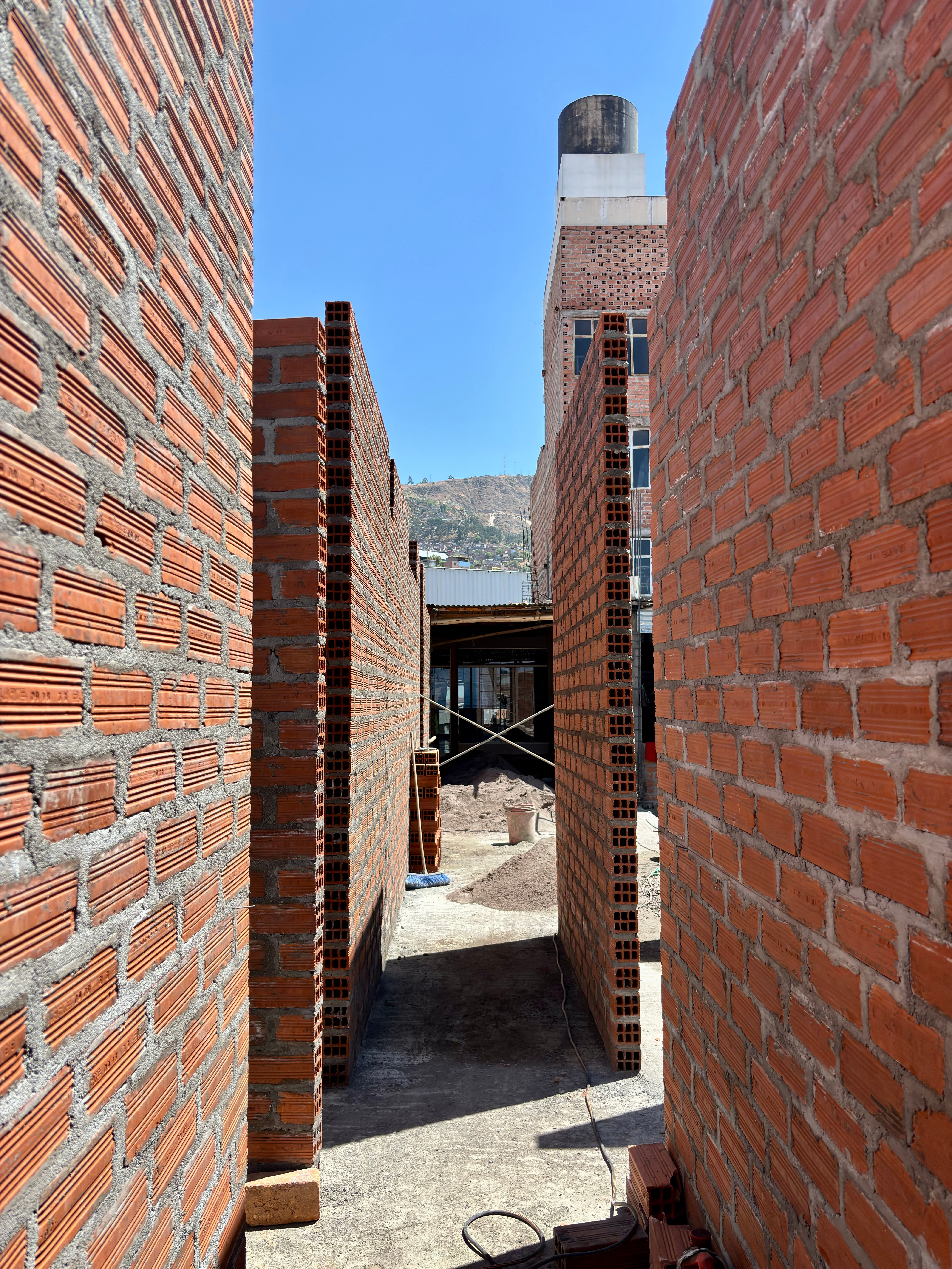 Fotomural Vista de la construcción de un muro de ladrillos en un día soleado en Ayacucho, Perú.