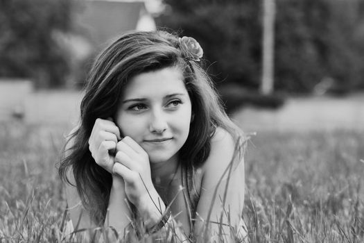 Graceful black and white portrait of a woman lying in the grass, exuding serenity.
