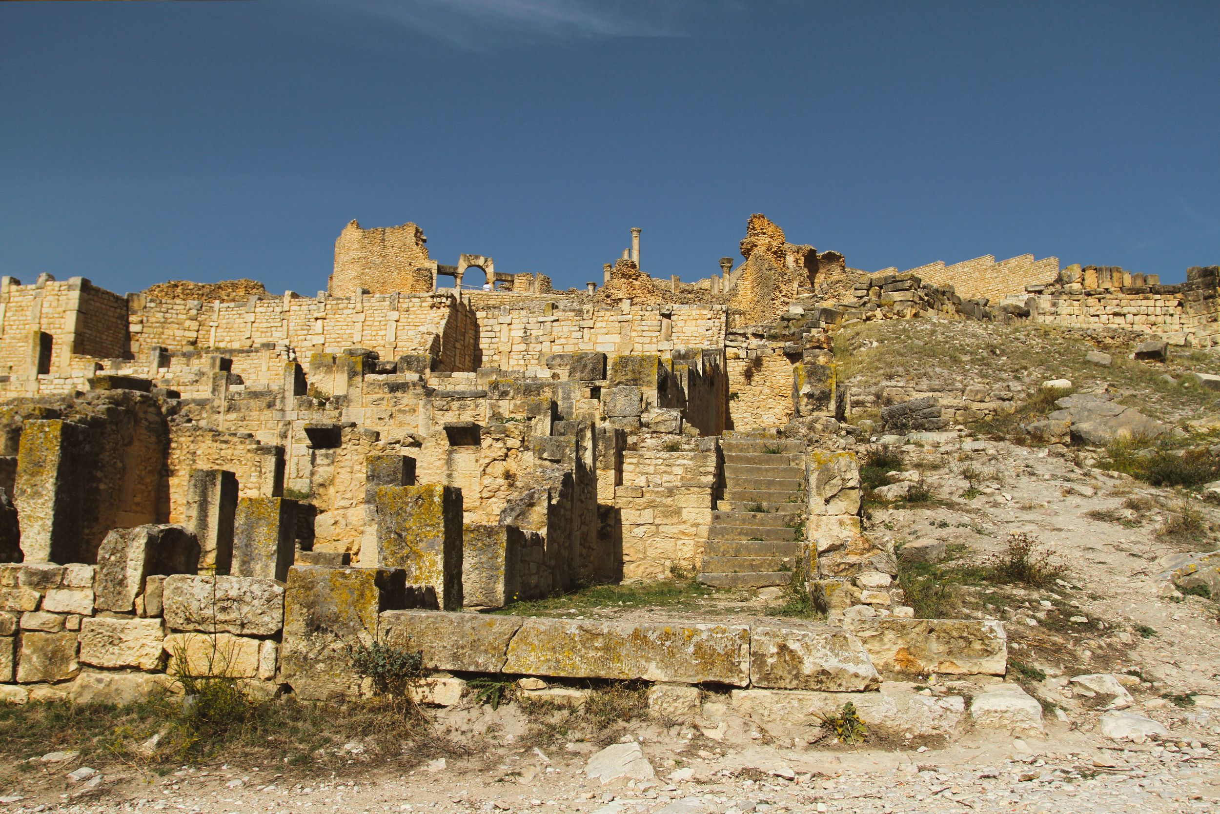 Beautiful view of Roman ruins under a clear blue sky in Béja Governorate, Tunisia.