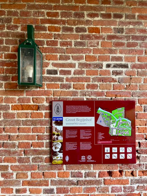 Free Map of the Groot Begijnhof at KU Leuven on a brick wall with a vintage lamp. Stock Photo