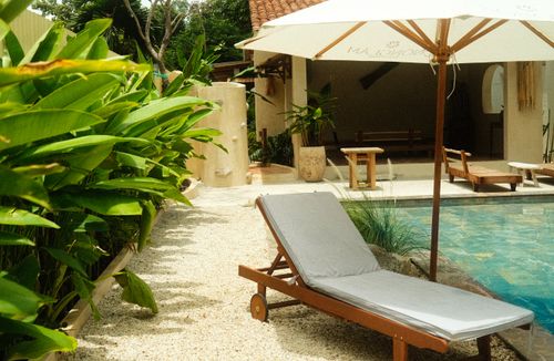 Free Relaxing poolside area with lounge chair, umbrella, and lush greenery in Ho Chi Minh City, Vietnam. Stock Photo