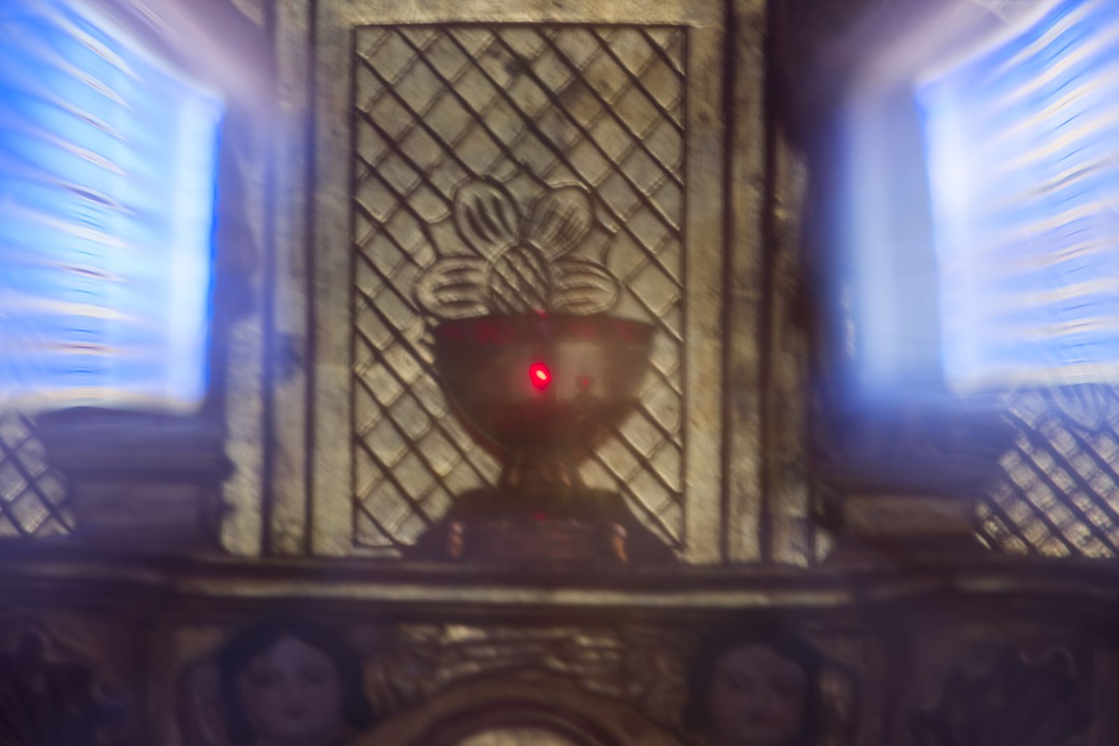 Lampe de sanctuaire rouge floutée sur un panneau d'autel sculpté, église française