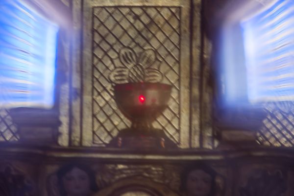 Lampe de sanctuaire rouge floutée sur un panneau d'autel sculpté, église française