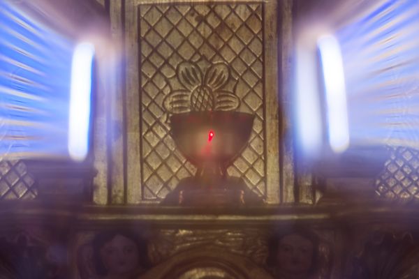 Lampe votive en pose longue sur un retable richement sculpté