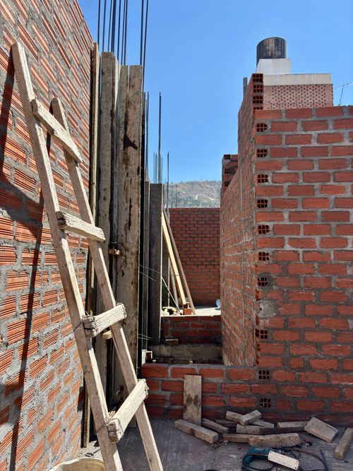 Free Unfinished brick walls and a wooden ladder at a construction site in Ayacucho, Peru under a clear blue sky. Stock Photo