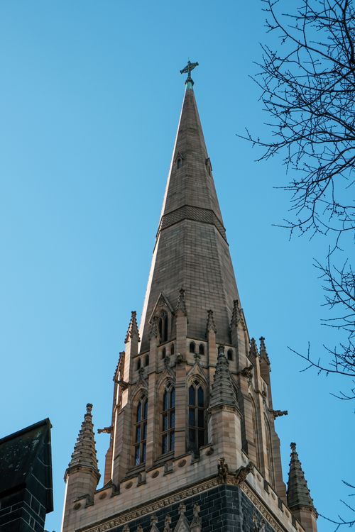 Free Stunning Gothic church spire reaching towards a bright blue sky, highlighting architectural detail. Stock Photo