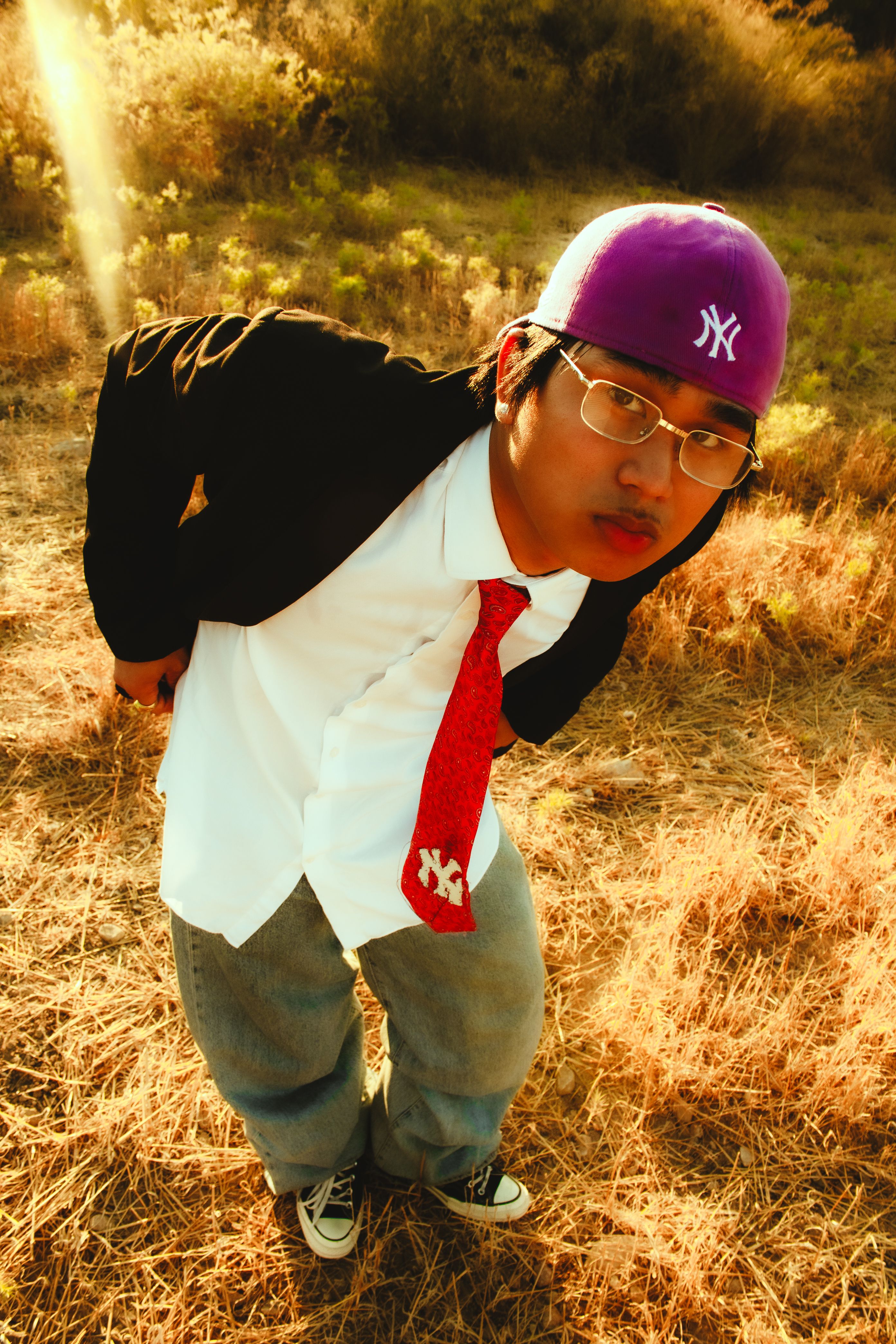 A stylish individual in casual urban fashion poses outdoors, blending streetwear with nature.