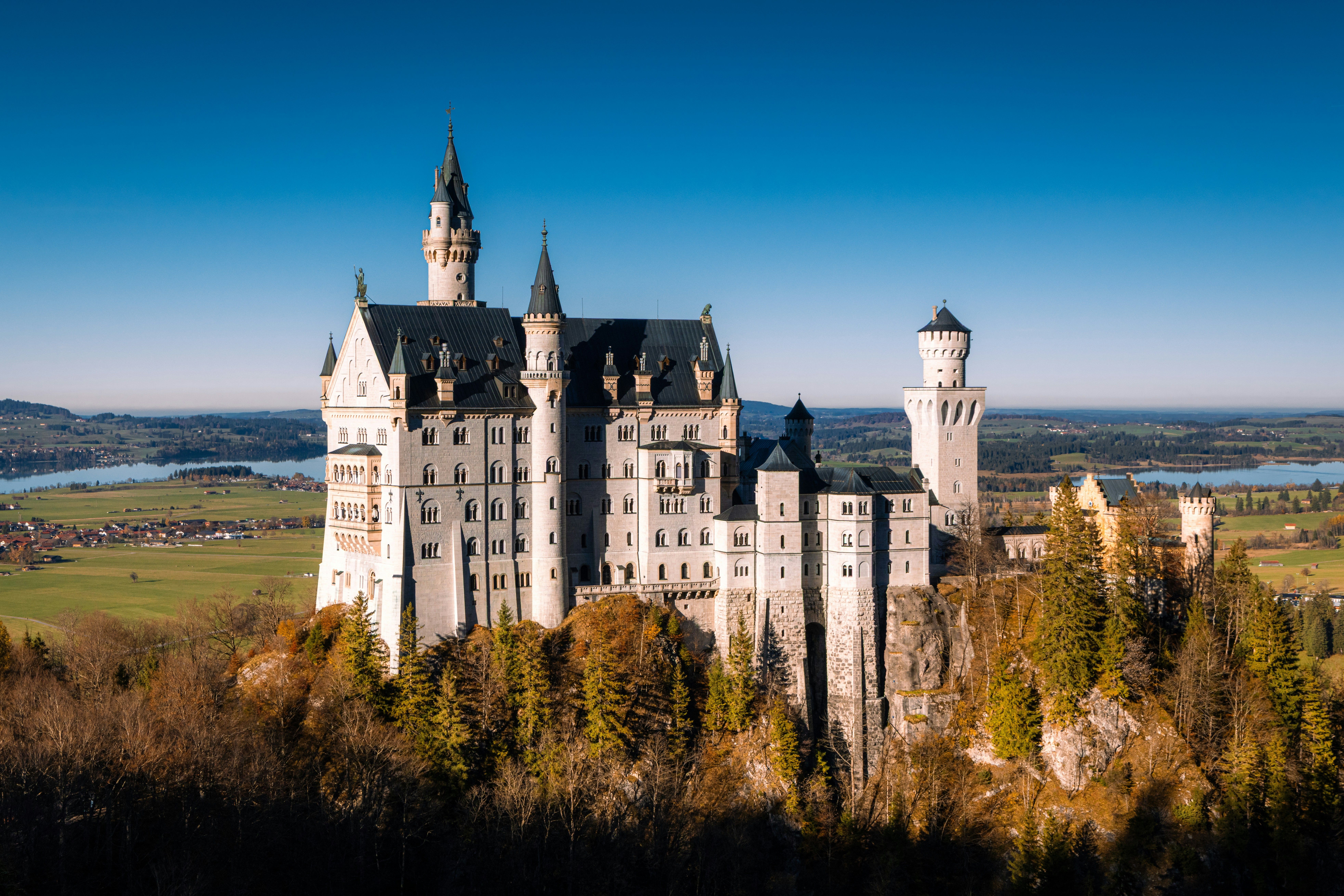 Aerial view of Neuschwanstein Castle surrounded by autumn foliage in Bavaria, Germany.