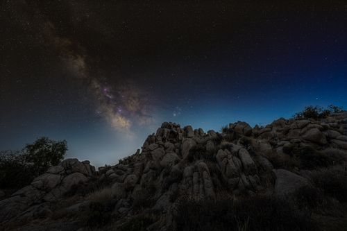 Free Stunning view of the Milky Way galaxy illuminating a rocky desert landscape under a starry night sky. Stock Photo