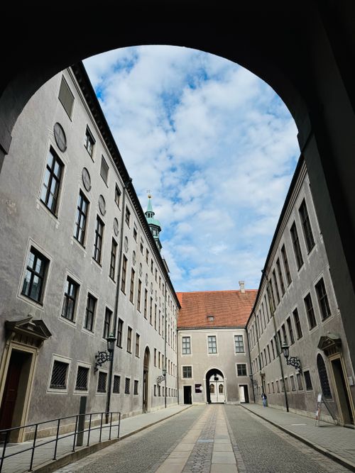Free Capture of a historic alleyway in Munich featuring classic architecture and a blue sky. Stock Photo