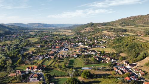 Free Picturesque aerial view of a Romanian village amidst rolling hills in summer. Stock Photo