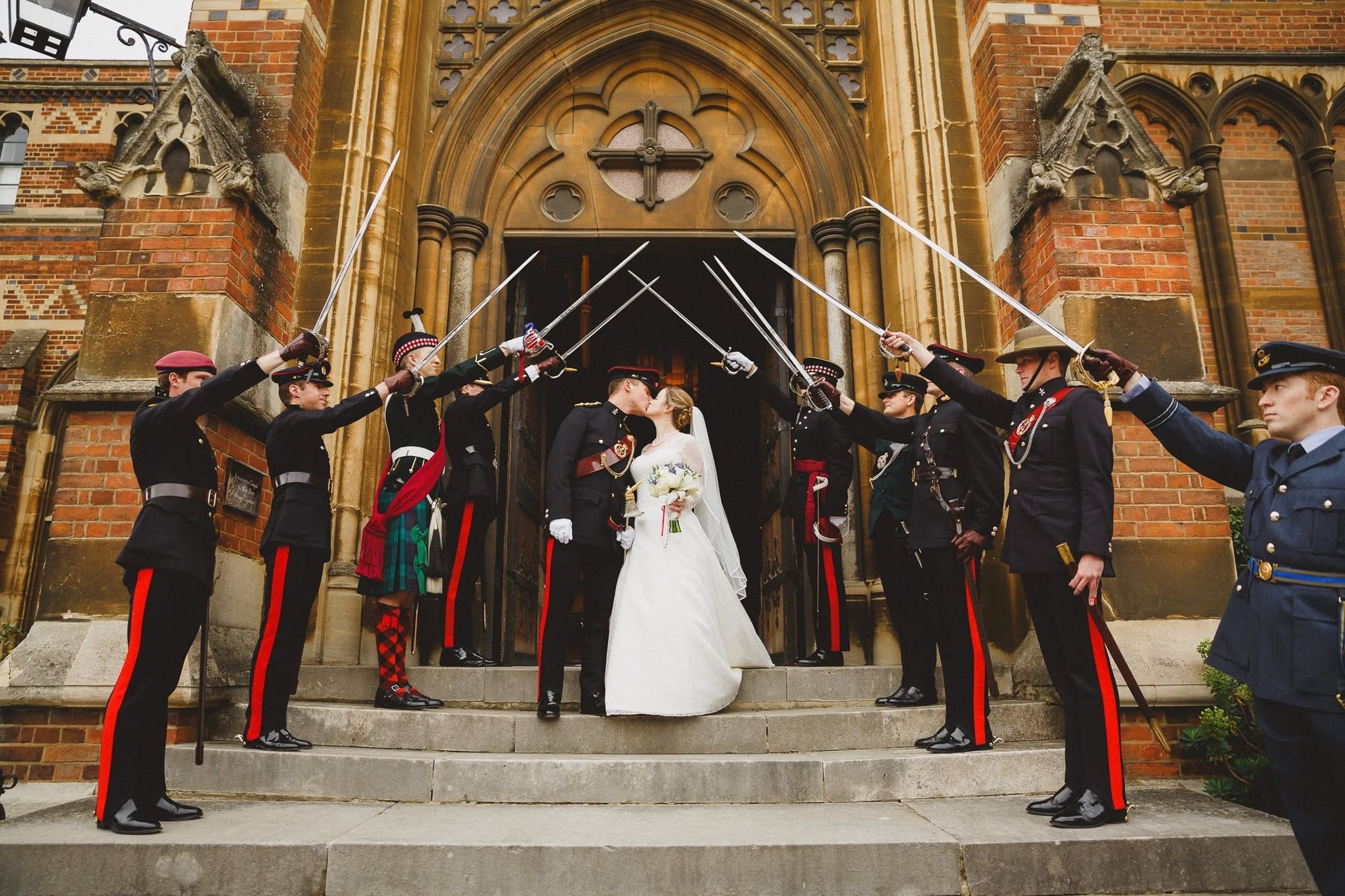 A couple kissing under a military arch at a historic church in England.