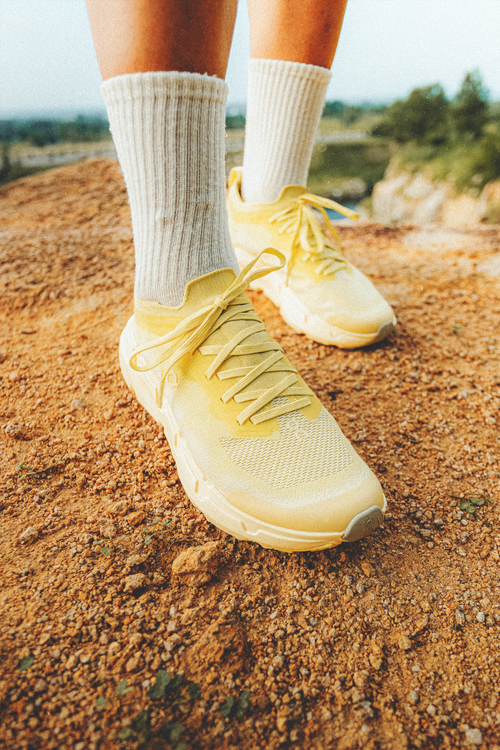 Free Close-up of yellow sneakers and socks on a rocky trail, conveying outdoor adventure in Ho Chi Minh City. Stock Photo