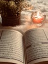 Photo Of An Open Book Beside Red Lighted Candle