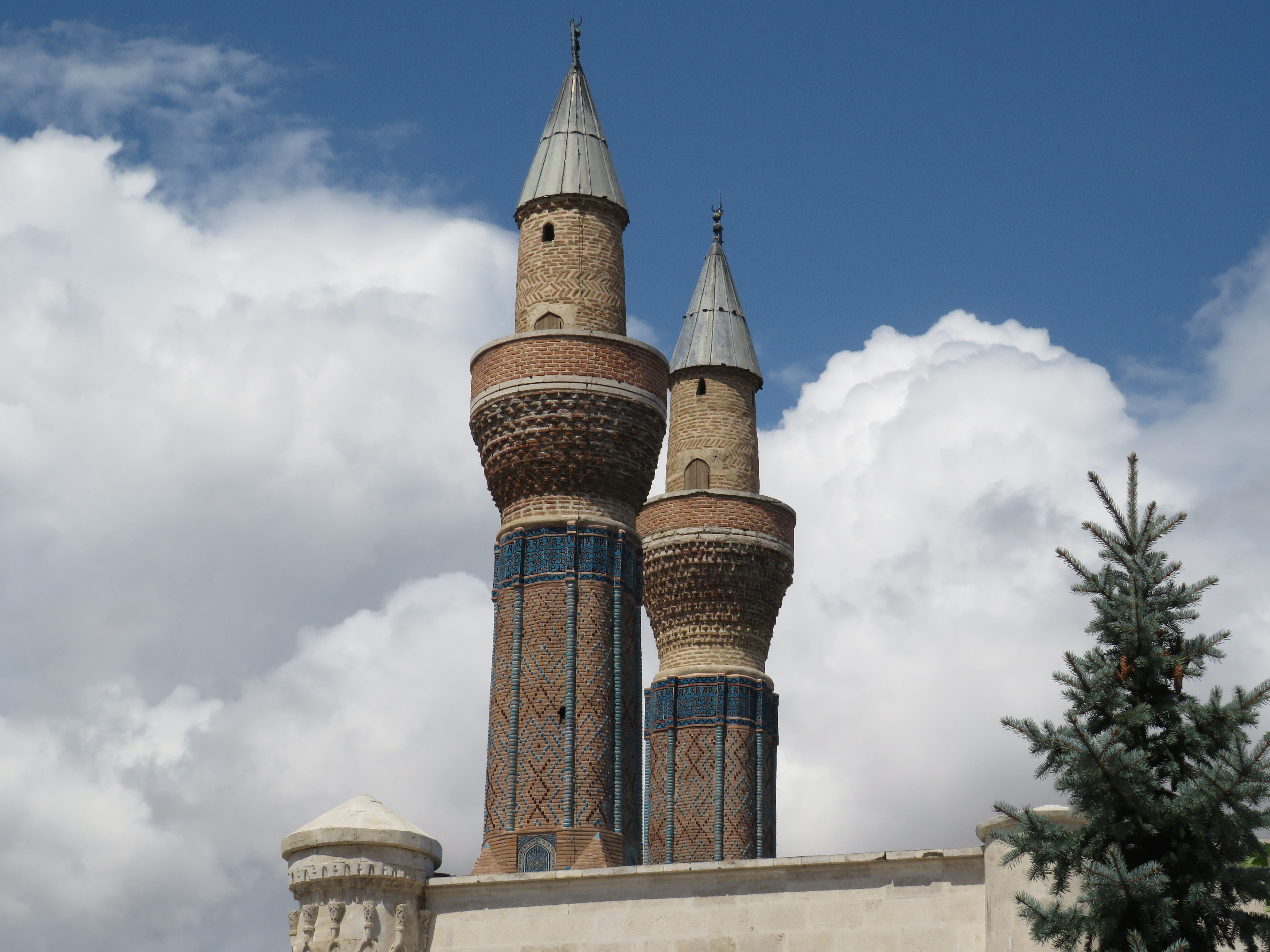 Exploring the twin minarets of the Gök Medrese in Sivas, Türkiye, under a bright day sky.