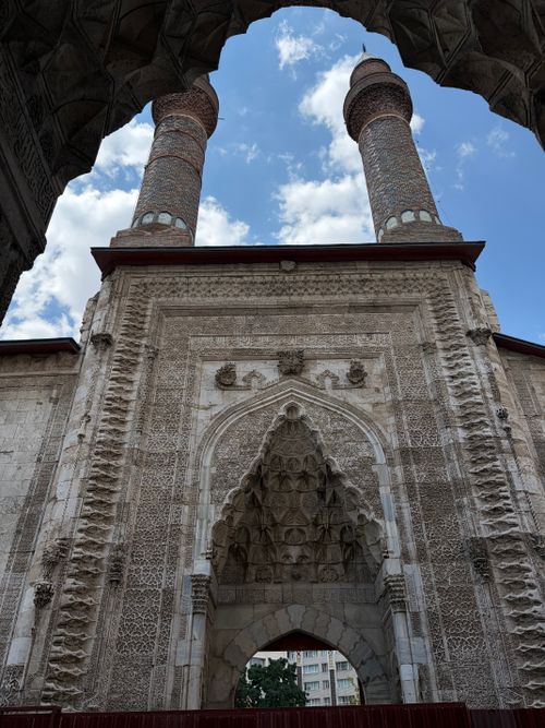 Free Ornate stonework of the Sivas Grand Mosque, featuring its twin minarets under a clear blue sky. Stock Photo
