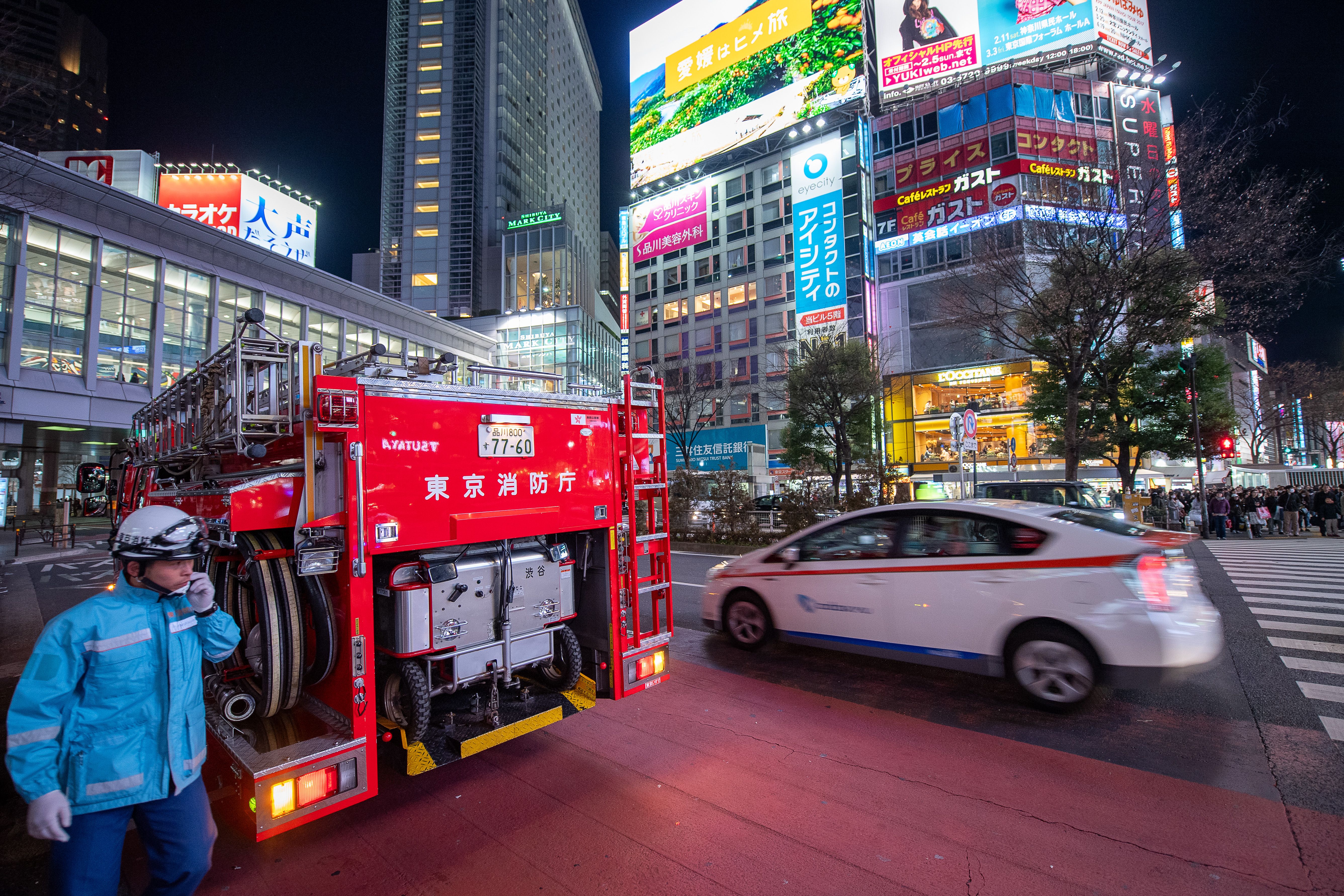 Fire truck and emergency responders at a city intersection at night.