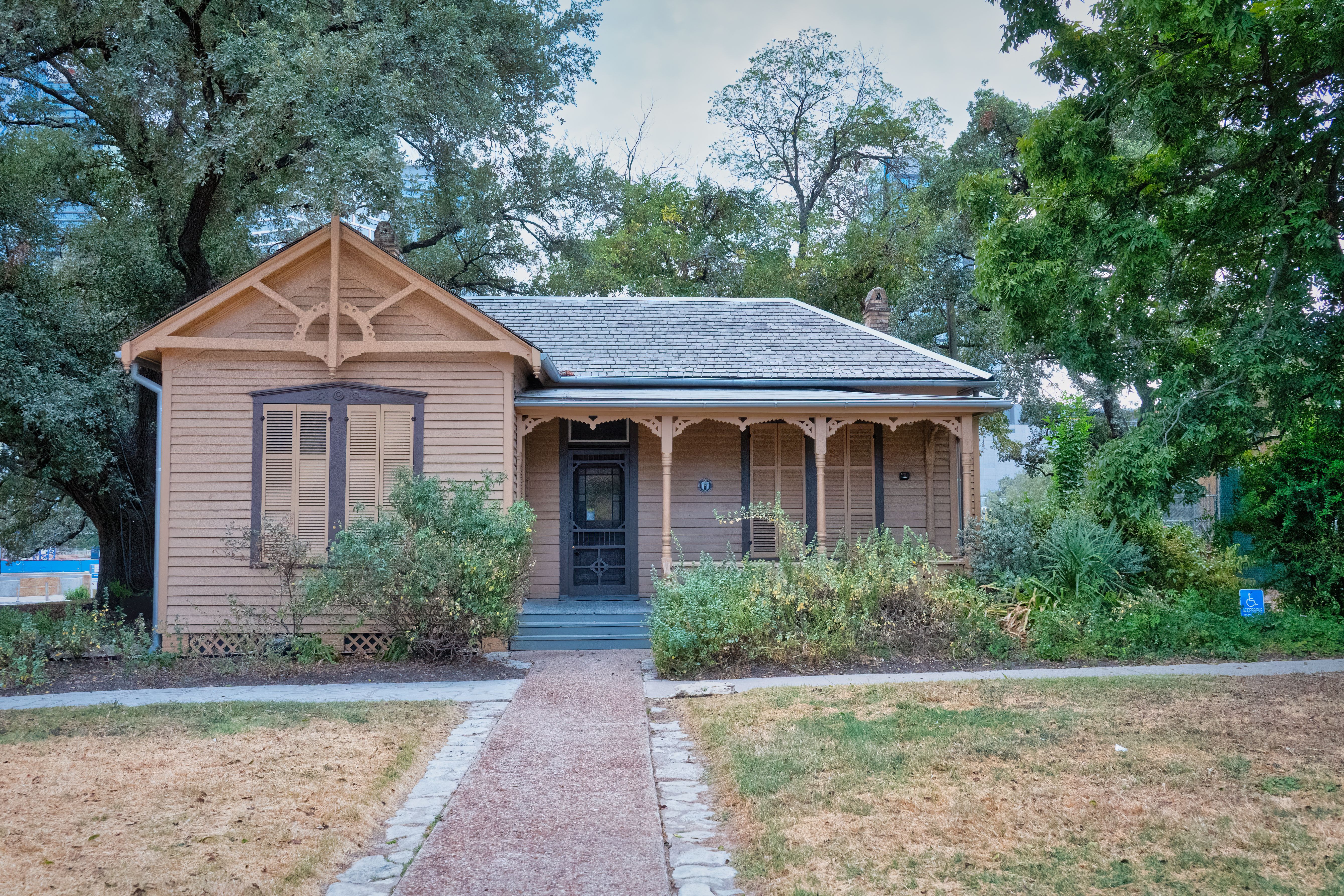 Historic wooden house surrounded by lush greenery in Austin, Texas.