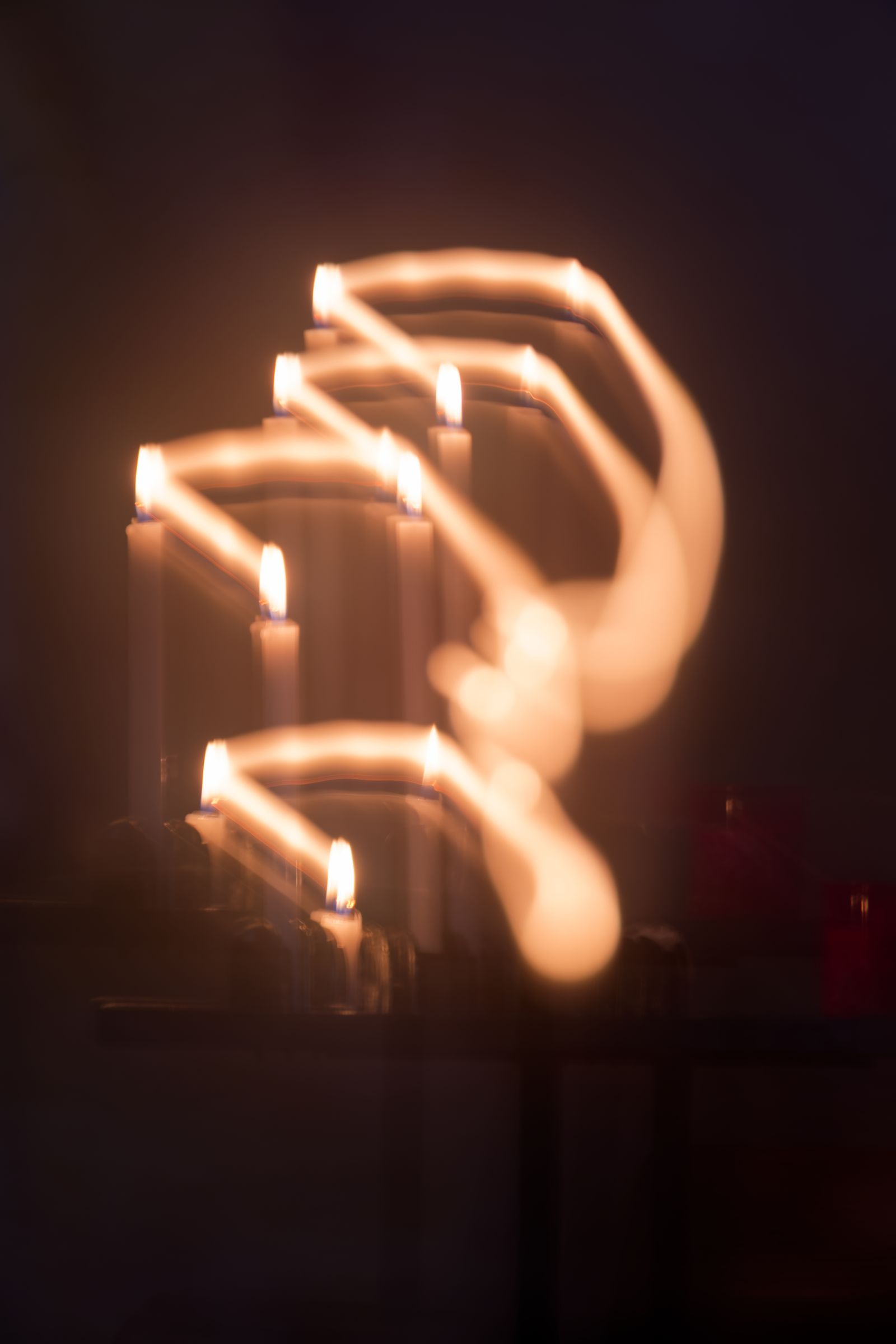 Traînées lumineuses abstraites de flammes de bougies, dans une église française sombre