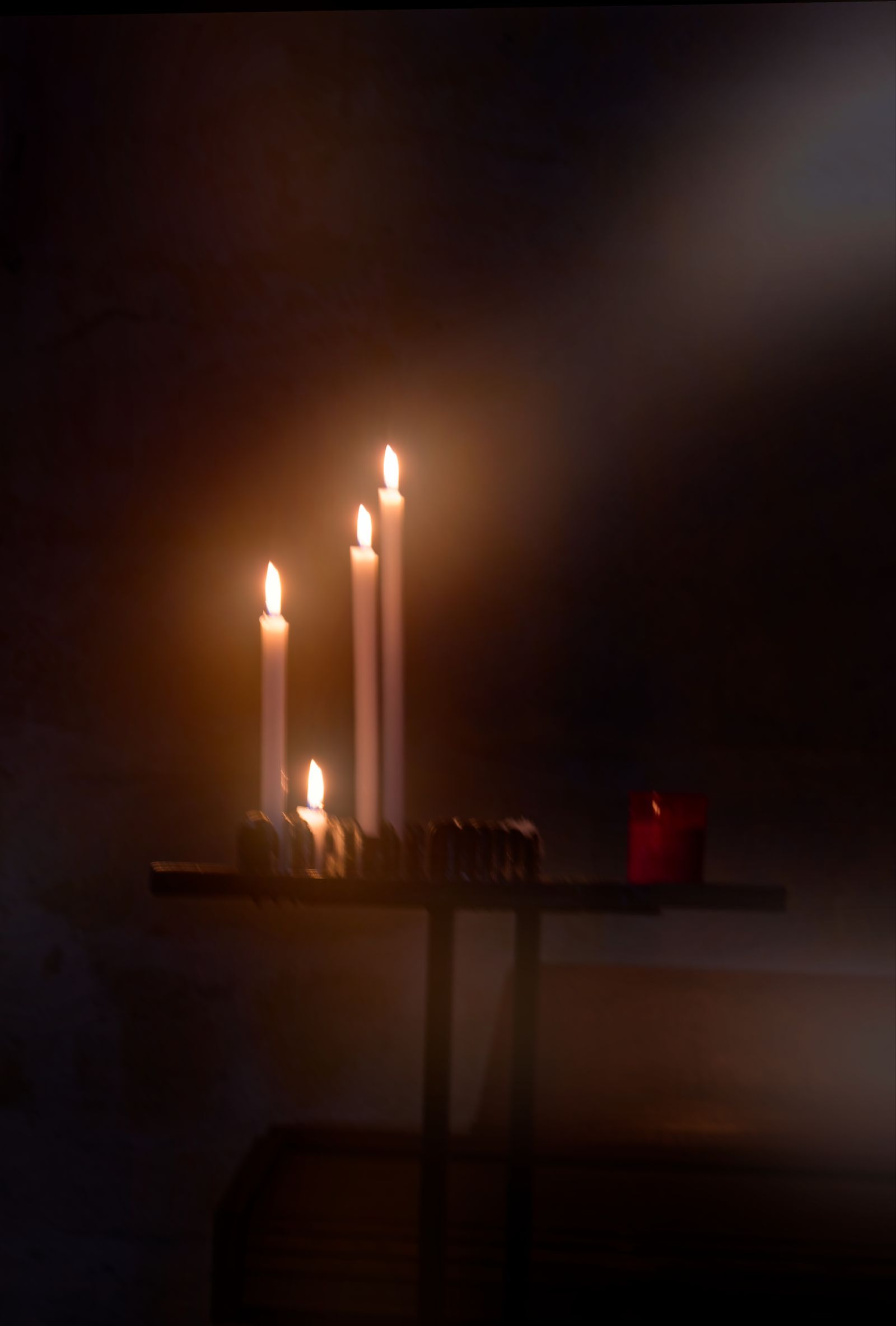 Plusieurs bougies commémoratives brillent doucement dans une chapelle française sombre