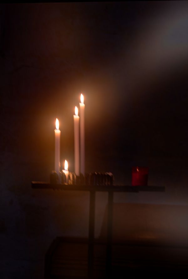 Plusieurs bougies commémoratives brillent doucement dans une chapelle française sombre