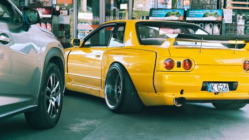 Free A vibrant yellow sports car parked at a gas station next to a silver SUV. Stock Photo