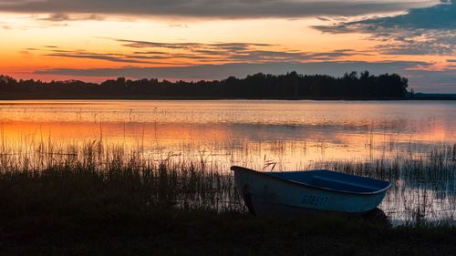 Free A serene sunset reflecting on Lake Braslav with a fishing boat in the foreground. Stock Photo