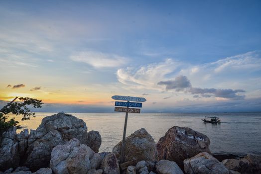 Tranquil sunset view over the rocks and sea at Cái Chiên Island in Vietnam with a boat in the distance.