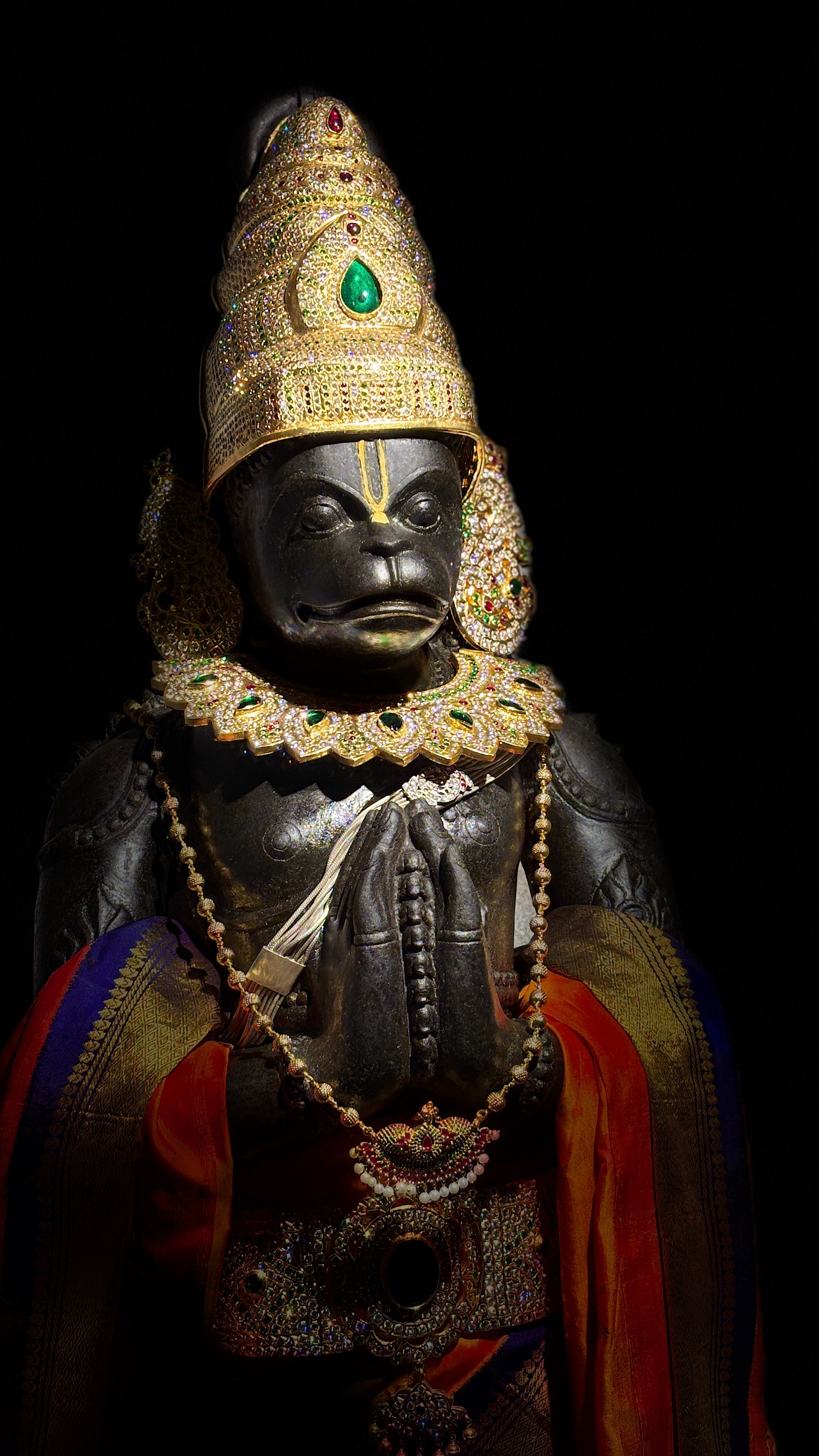 Intricately decorated stone statue of Hindu deity with golden attire and jewelry, symbolizing divine power.